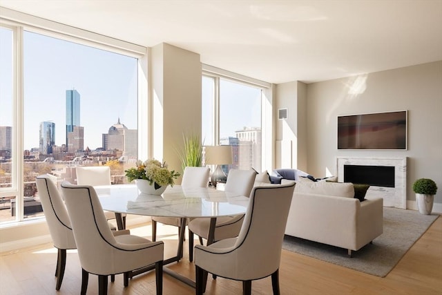 dining space with a fireplace, light hardwood / wood-style floors, and expansive windows