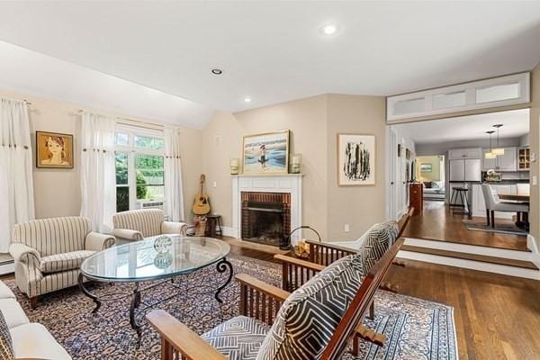 living area with wood finished floors, recessed lighting, a fireplace, baseboards, and vaulted ceiling