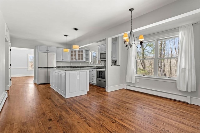 kitchen featuring a sink, glass insert cabinets, baseboard heating, appliances with stainless steel finishes, and dark wood-style flooring