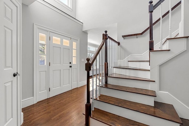 foyer entrance with a high ceiling, stairway, wood finished floors, and baseboards