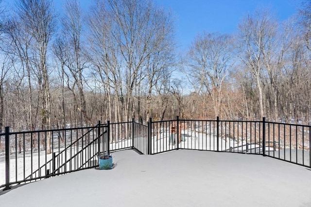 snow covered patio with a forest view