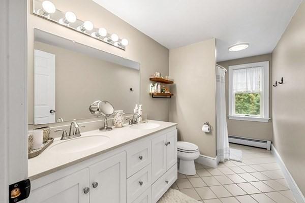 bathroom with a sink, a baseboard heating unit, toilet, and tile patterned floors