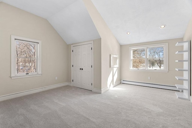 unfurnished bedroom with a baseboard heating unit, vaulted ceiling, and carpet floors