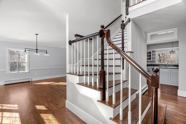 staircase with crown molding, wood finished floors, baseboards, and baseboard heating