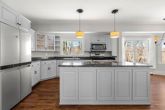 kitchen featuring open shelves, a sink, stainless steel appliances, dark wood-type flooring, and a center island