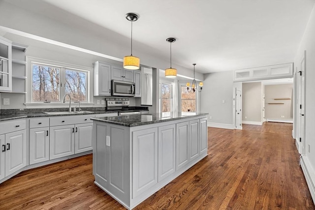 kitchen with a sink, appliances with stainless steel finishes, a wealth of natural light, and a center island