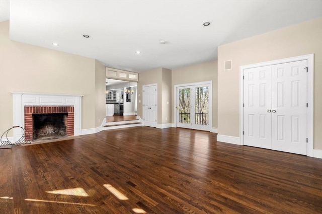 unfurnished living room with visible vents, wood finished floors, recessed lighting, baseboards, and a brick fireplace