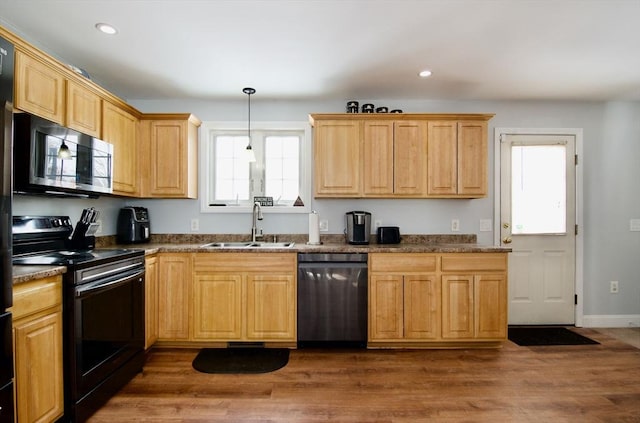 kitchen with sink, pendant lighting, dark wood-type flooring, and black appliances