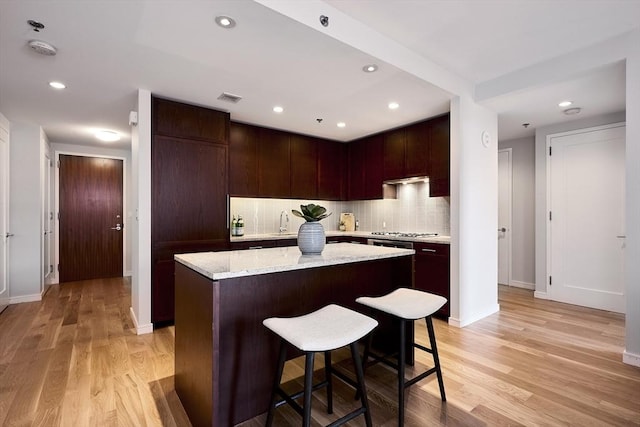 580 Washington St Unit 10F, Boston, MA 02111 - kitchen with a center island, light wood-style floors, decorative backsplash, a kitchen breakfast bar, and recessed lighting