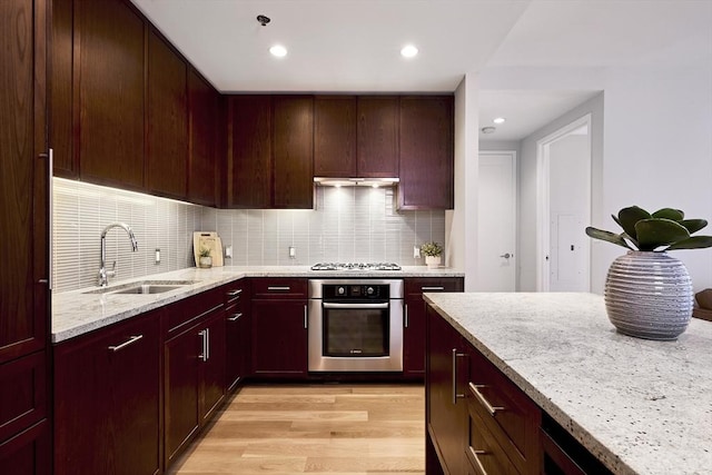 580 Washington St Unit 10F, Boston, MA 02111 - kitchen featuring stainless steel oven, light stone countertops, tasteful backsplash, light wood-style floors, and reddish brown cabinets