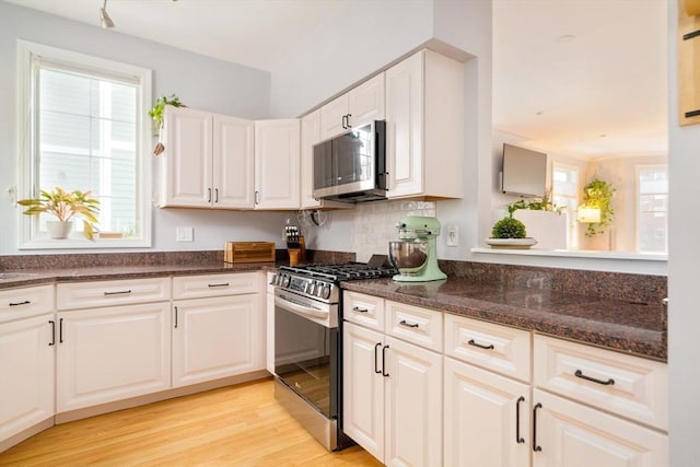 kitchen featuring stainless steel appliances, a wealth of natural light, white cabinets, and light hardwood / wood-style floors