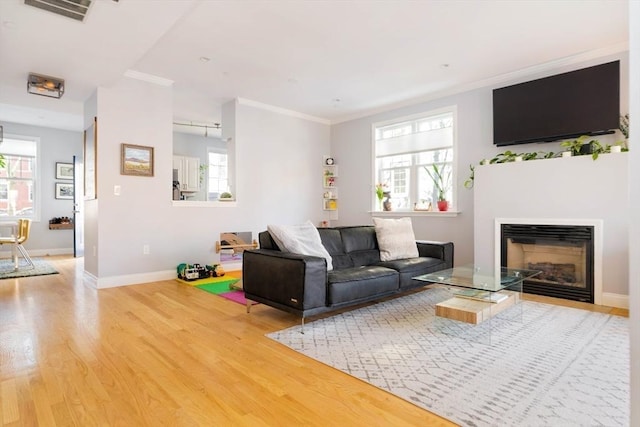 living room featuring crown molding, a healthy amount of sunlight, and wood-type flooring