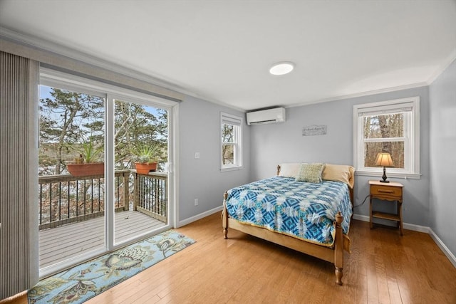 bedroom featuring hardwood / wood-style floors, ornamental molding, access to outside, and a wall mounted AC