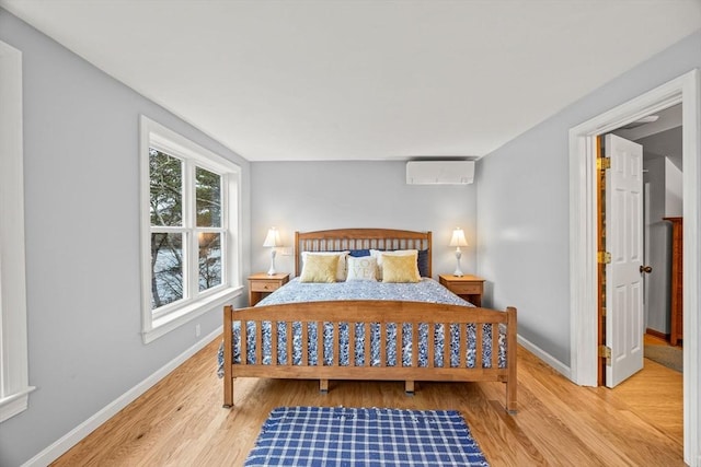 bedroom with light hardwood / wood-style floors and an AC wall unit