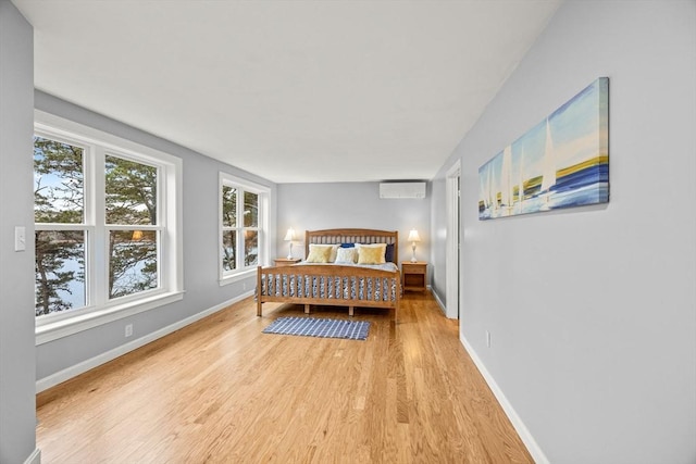 bedroom featuring an AC wall unit and light hardwood / wood-style floors