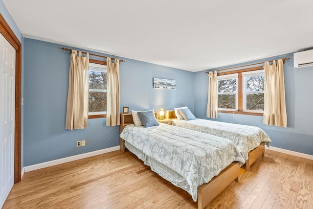 bedroom with light hardwood / wood-style flooring and a wall unit AC