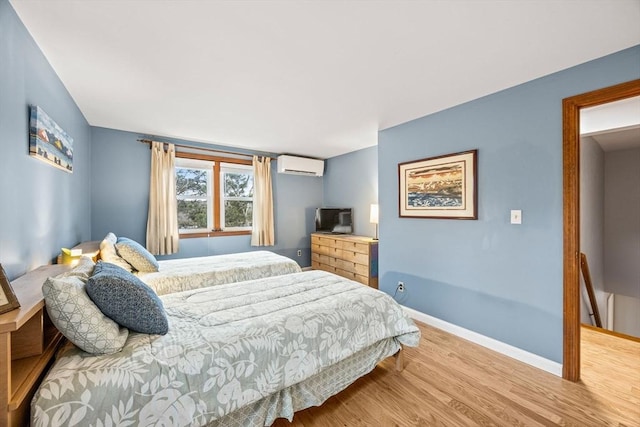 bedroom with hardwood / wood-style floors and a wall unit AC