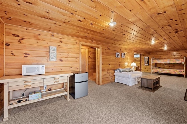 interior space featuring carpet flooring, stainless steel fridge, wood walls, and wood ceiling