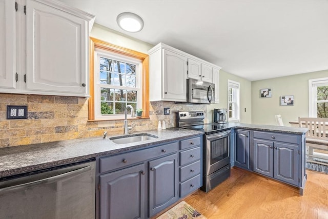 kitchen with a wealth of natural light, sink, stainless steel appliances, light hardwood / wood-style flooring, and white cabinets