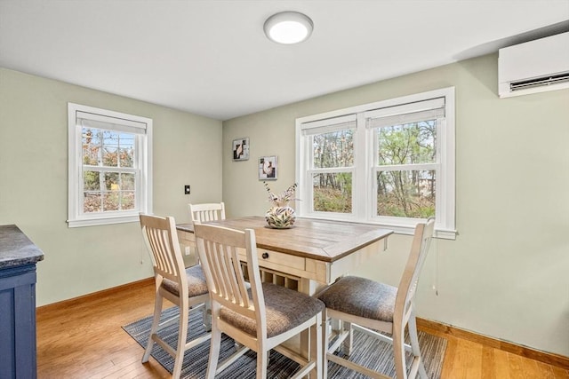 dining area with a healthy amount of sunlight, light wood-type flooring, and a wall unit AC