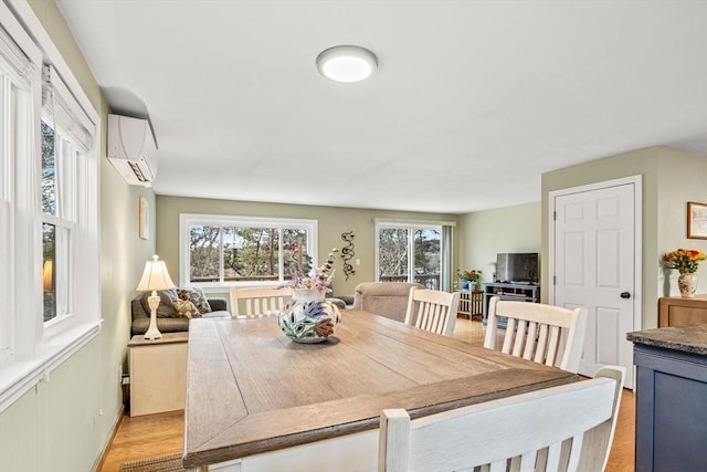 dining room with light wood-type flooring and a wall mounted AC