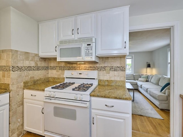 440 Forest St, Waltham, MA 02452 - kitchen with white appliances, white cabinetry, light wood-style floors, stone counters, and open floor plan