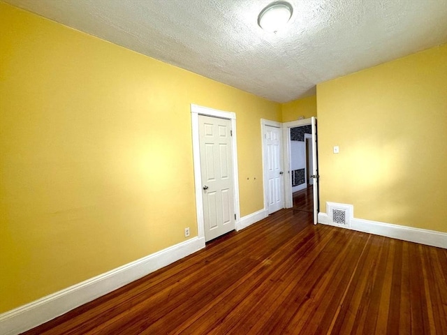 unfurnished bedroom with baseboards, a textured ceiling, visible vents, and wood finished floors