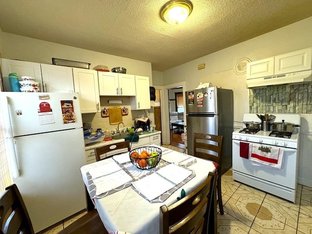 kitchen with tasteful backsplash, white appliances, white cabinets, and under cabinet range hood