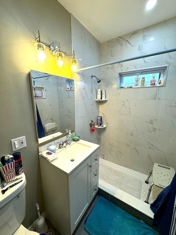 bathroom featuring toilet, tiled shower, and vanity