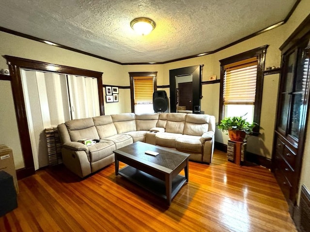 living area with a textured ceiling, ornamental molding, and hardwood / wood-style floors