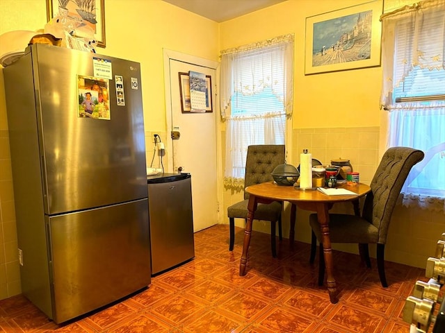 interior space featuring a wealth of natural light, freestanding refrigerator, refrigerator, and tile walls