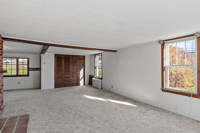 interior space with radiator, a closet, carpet, and beamed ceiling