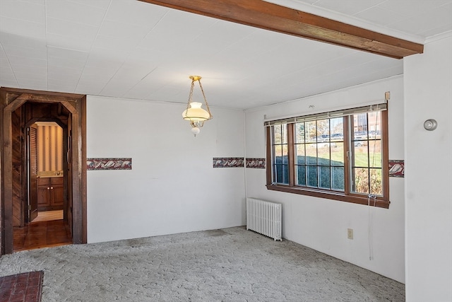 carpeted empty room with beamed ceiling and radiator