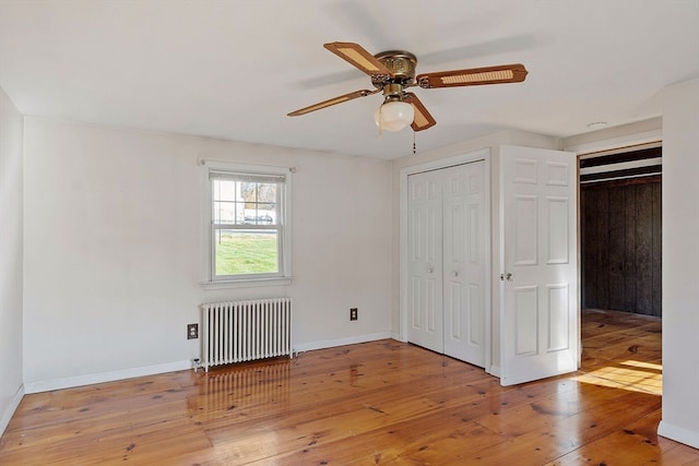 unfurnished bedroom featuring light hardwood / wood-style flooring, ceiling fan, a closet, and radiator heating unit