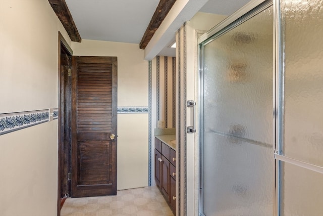 bathroom featuring beam ceiling, vanity, and walk in shower