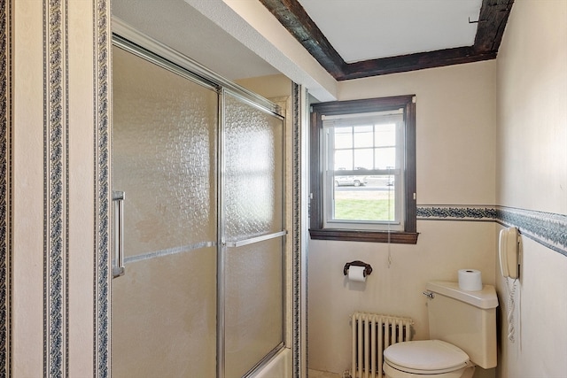 bathroom featuring a shower with door, crown molding, radiator heating unit, and toilet