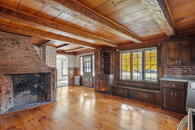 interior space with a fireplace, beam ceiling, wooden ceiling, light wood-type flooring, and radiator heating unit