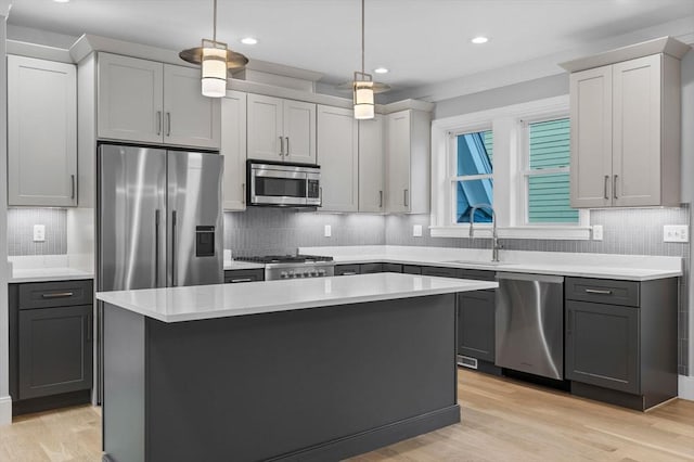 kitchen featuring pendant lighting, gray cabinetry, stainless steel appliances, light hardwood / wood-style floors, and a kitchen island