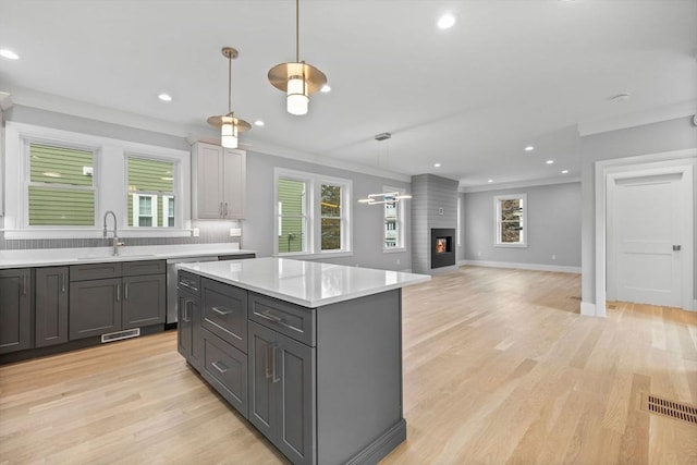 kitchen with a kitchen island, a fireplace, decorative light fixtures, sink, and gray cabinetry