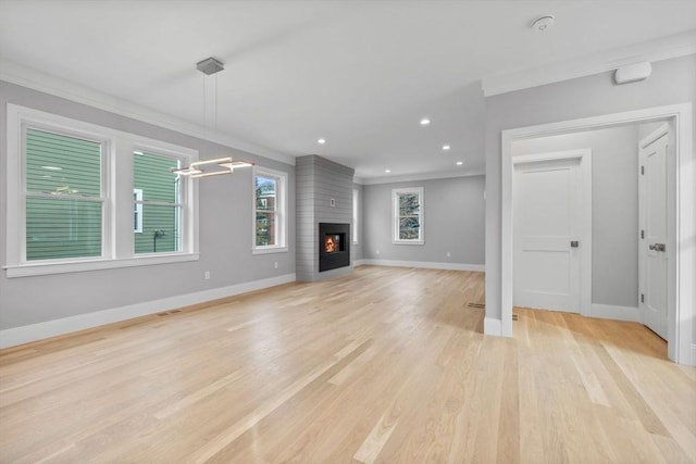 unfurnished living room featuring crown molding, a large fireplace, and light wood-type flooring