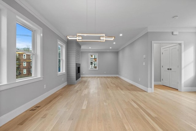 unfurnished living room featuring a fireplace, a healthy amount of sunlight, and ornamental molding