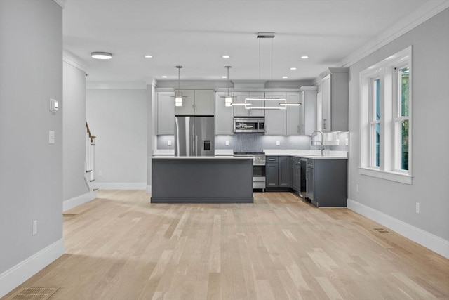 kitchen featuring backsplash, stainless steel appliances, crown molding, decorative light fixtures, and gray cabinets