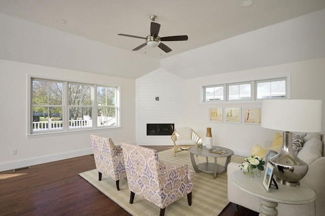 living room featuring dark hardwood / wood-style flooring, ceiling fan, a large fireplace, and lofted ceiling