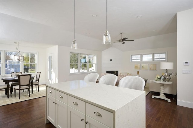 kitchen with ceiling fan, a center island, hanging light fixtures, a fireplace, and white cabinets