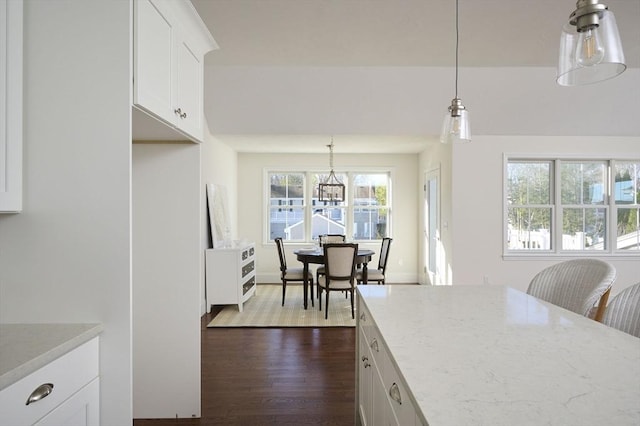 kitchen featuring decorative light fixtures, light stone counters, white cabinetry, and plenty of natural light