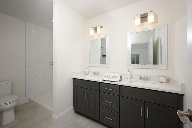 bathroom with tile patterned floors, vanity, a tile shower, and toilet