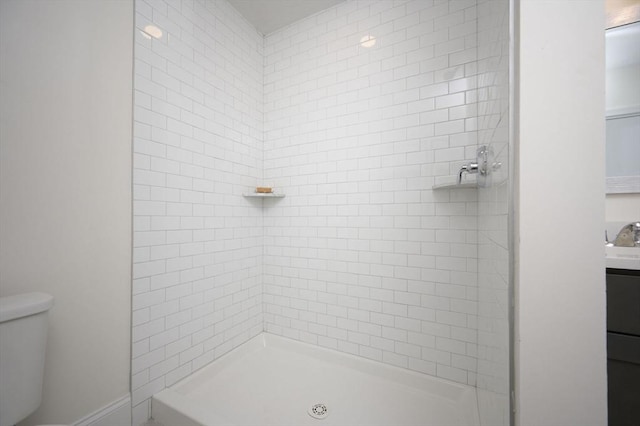 bathroom featuring vanity, toilet, and tiled shower