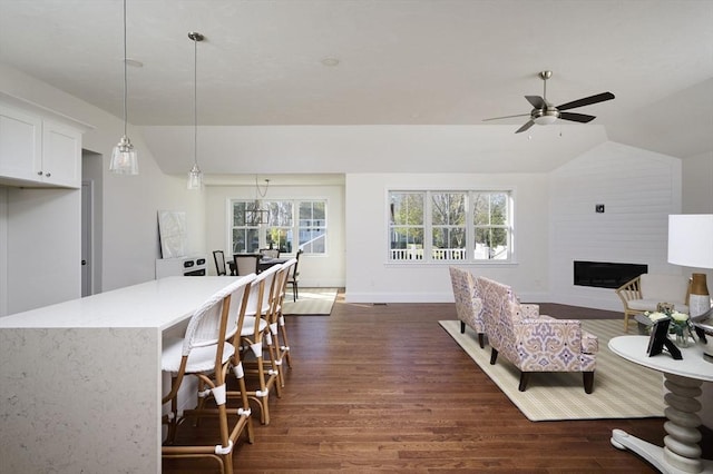 interior space featuring ceiling fan, dark hardwood / wood-style flooring, a fireplace, and vaulted ceiling