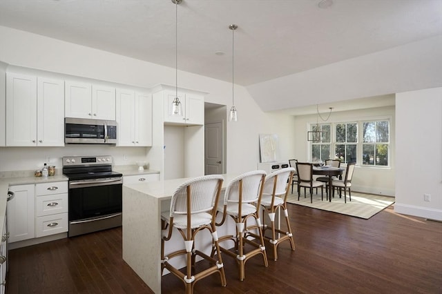 kitchen with white cabinetry, a center island, hanging light fixtures, and appliances with stainless steel finishes