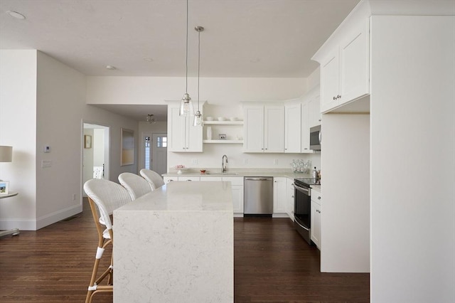 kitchen featuring white cabinetry, sink, hanging light fixtures, and appliances with stainless steel finishes